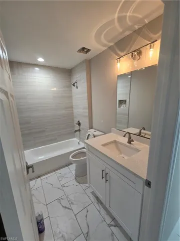 Full bathroom featuring tiled shower / bath combo, vanity, and toilet