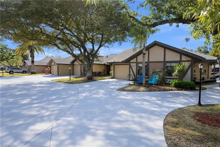 View of front facade with stucco siding, curved driveway, and an attached garage
