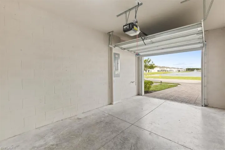 Garage with electric panel, a garage door opener, and a residential view