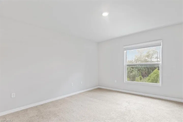 Spare room featuring carpet flooring and baseboards