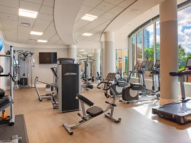 Workout area featuring a drop ceiling and a wall of windows