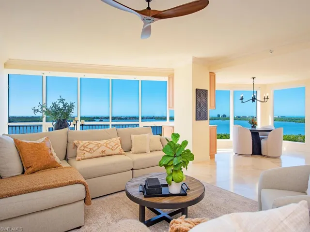 Living area with a water view, a chandelier, a ceiling fan, plenty of natural light, and crown molding