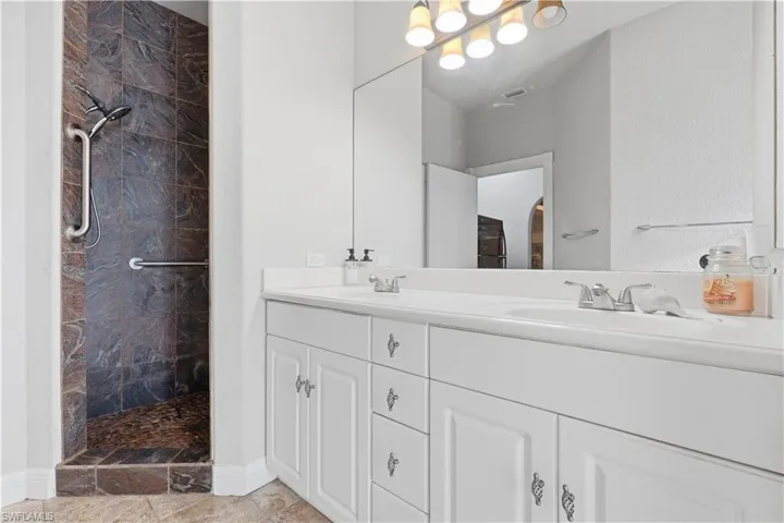 Full bathroom with double vanity and a shower stall