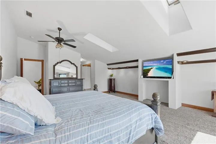 Bedroom with a skylight, light colored carpet, a ceiling fan, and lofted ceiling