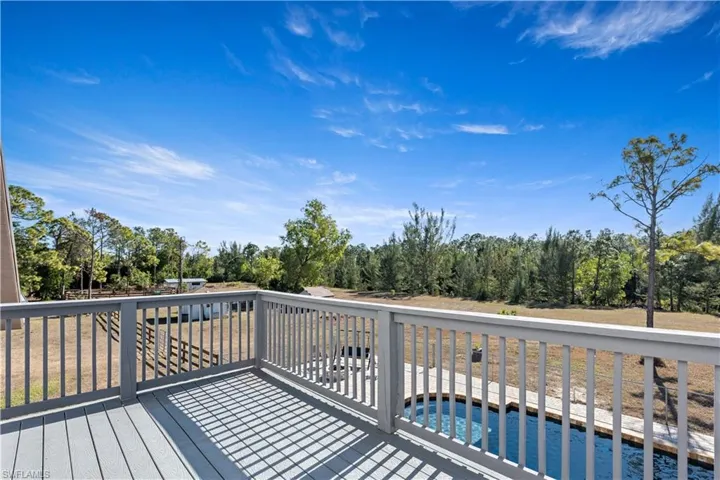 Wooden deck featuring view of wooded area and an outdoor pool