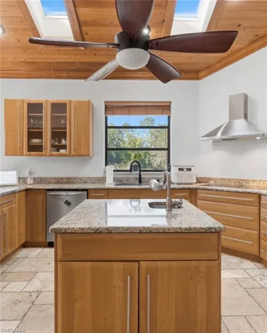 Kitchen featuring a skylight, stone tile flooring, light stone countertops, and wooden ceiling