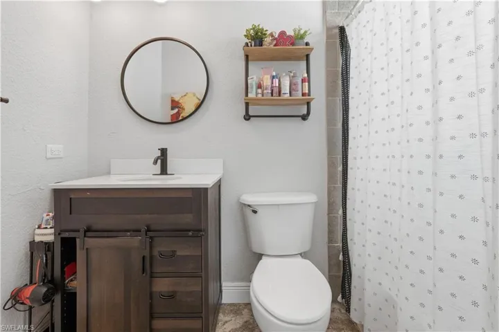 Full bathroom featuring vanity, a shower with curtain, and a textured wall