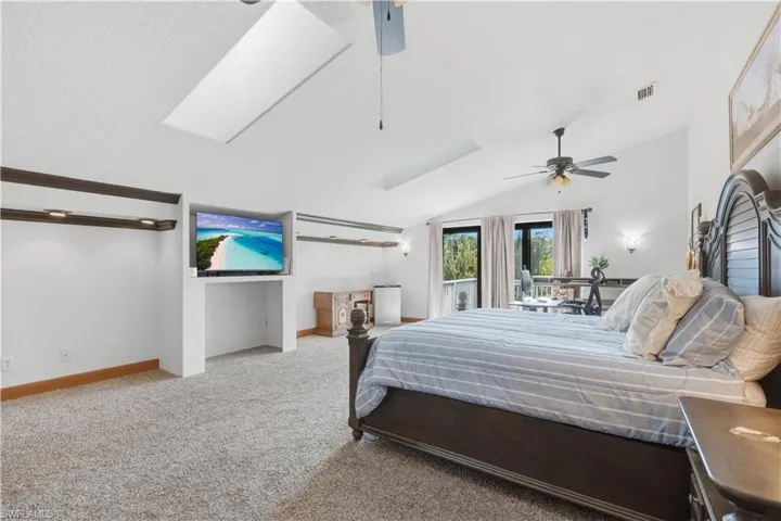 Bedroom with lofted ceiling, light colored carpet, and a ceiling fan