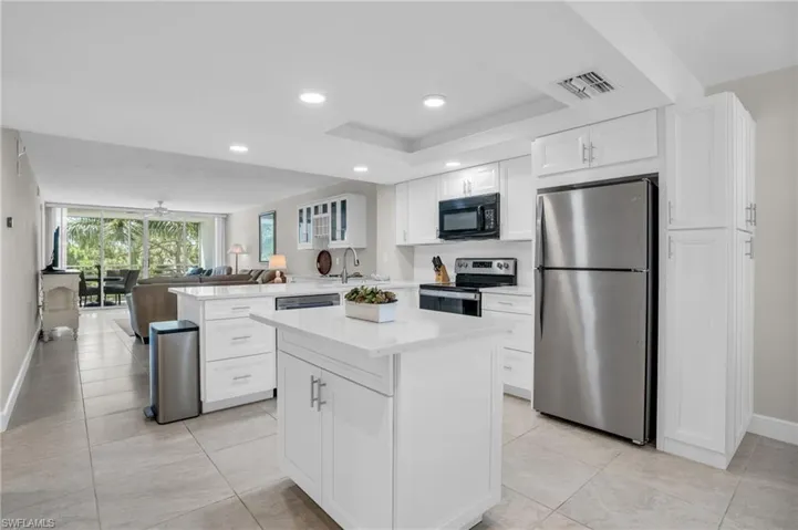Kitchen featuring appliances with stainless steel finishes, white cabinetry, light tile flooring, and kitchen island