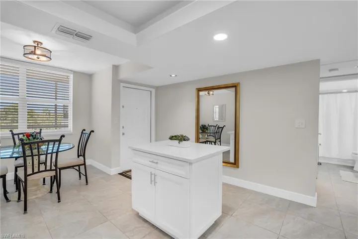 Kitchen with a center island, white cabinets, and light tile floors