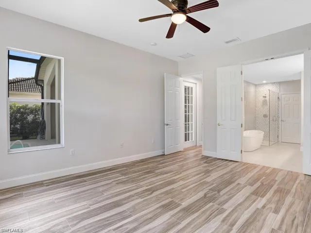 Primary bedroom with wood tiled floors, a ceiling fan, and ensuite bathroom