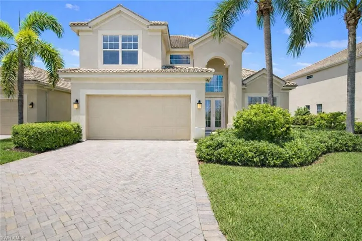 Mediterranean / spanish-style home with a garage, decorative driveway, a front yard, stucco siding, and a tile roof