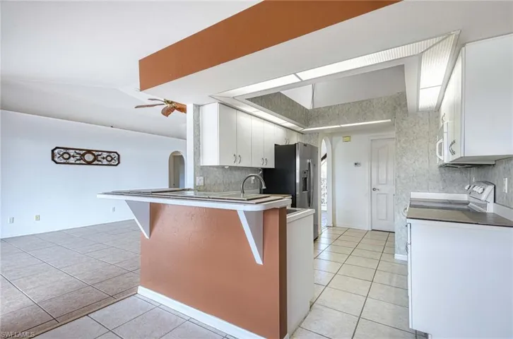 Kitchen with ceiling fan, white cabinetry, kitchen peninsula, and light tile patterned floors