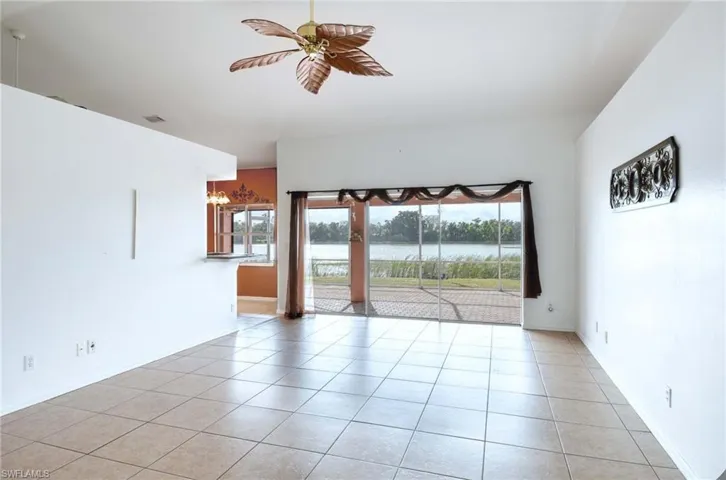 Tiled empty room featuring ceiling fan and a water view