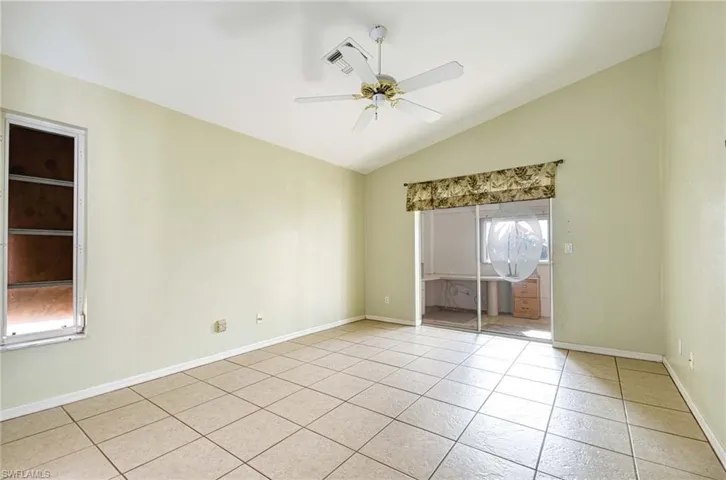 Empty room featuring a healthy amount of sunlight, light tile patterned floors, and vaulted ceiling