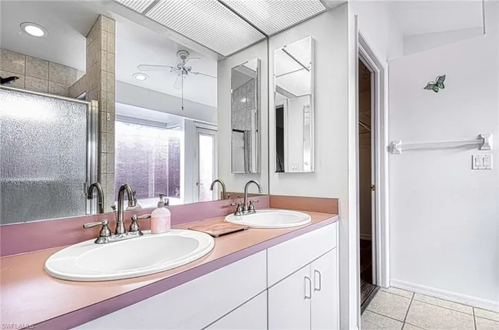 Bathroom featuring ceiling fan, tile patterned flooring, vanity, and an enclosed shower