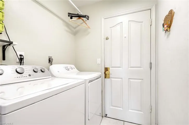 Laundry room with washer and clothes dryer and light tile patterned floors