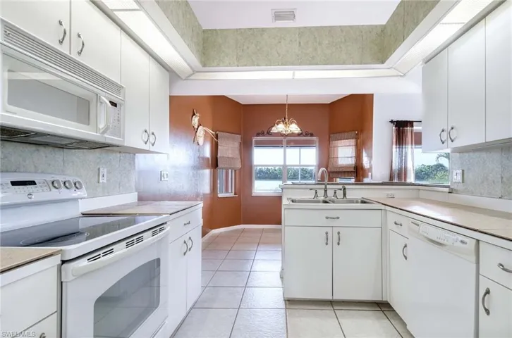 Kitchen featuring white appliances, white cabinetry, and sink