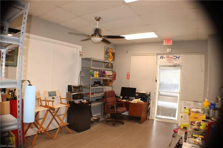 Office with ceiling fan, light tile patterned floors, and a drop ceiling