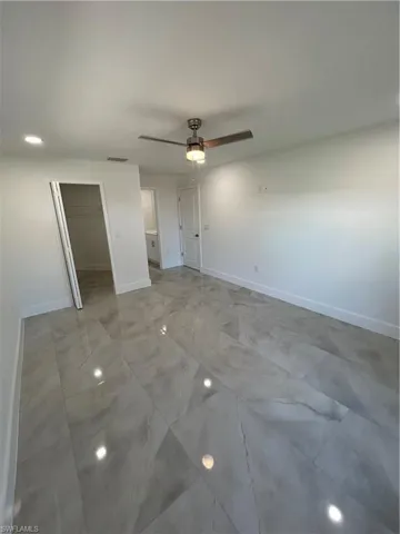 Unfurnished bedroom featuring a walk in closet, ceiling fan, and a closet