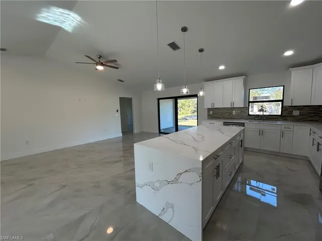 Kitchen featuring a wealth of natural light, a center island, white cabinets, and lofted ceiling