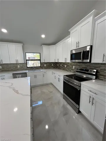 Kitchen featuring light stone countertops, white cabinets, and stainless steel range oven