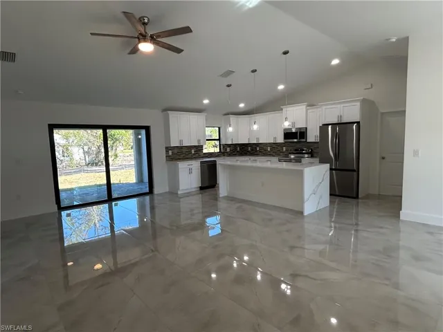 Kitchen featuring stainless steel appliances, ceiling fan, pendant lighting, white cabinets, and a kitchen island