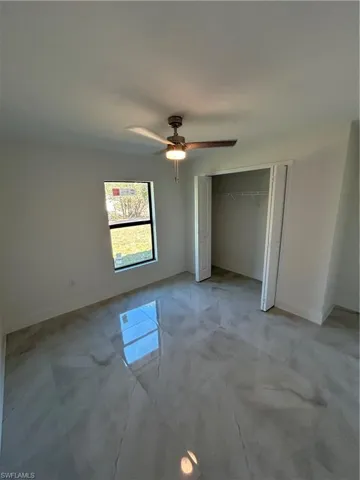 Unfurnished bedroom with ceiling fan and a closet