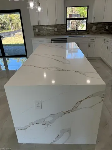 Kitchen with tasteful backsplash, plenty of natural light, hanging light fixtures, and sink