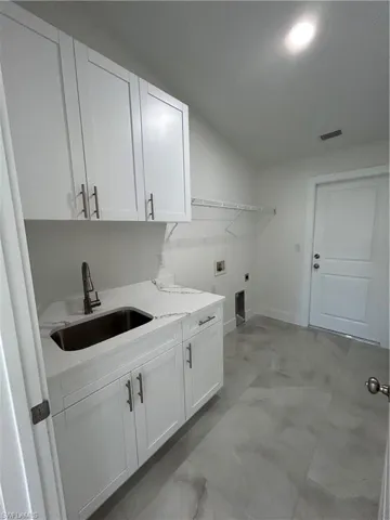 Laundry room with hookup for an electric dryer, washer hookup, cabinets, and sink
