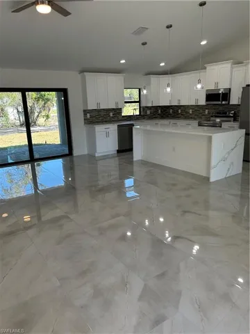 Kitchen with a wealth of natural light, white cabinetry, and hanging light fixtures