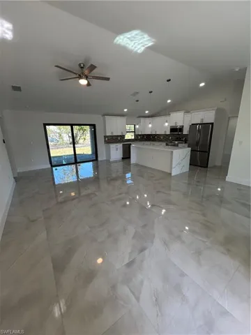 Unfurnished living room with vaulted ceiling and ceiling fan