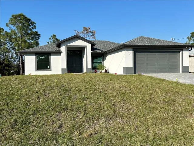 View of front facade featuring a front yard and a garage
