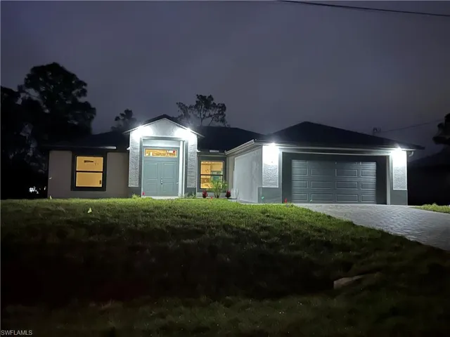 Ranch-style home featuring a garage and a lawn