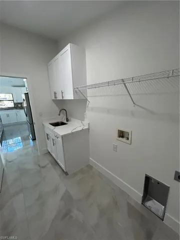Clothes washing area featuring cabinets, sink, and hookup for a washing machine