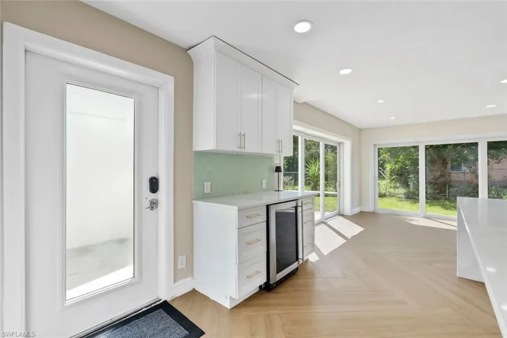 Integrated beverage refrigerator, white cabinetry with gold-tone hardware, green subway tile backsplash