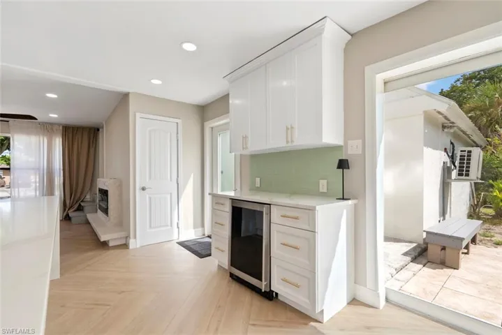 White shaker cabinetry with gold-tone hardware, integrated beverage cooler, light green subway tile backsplash