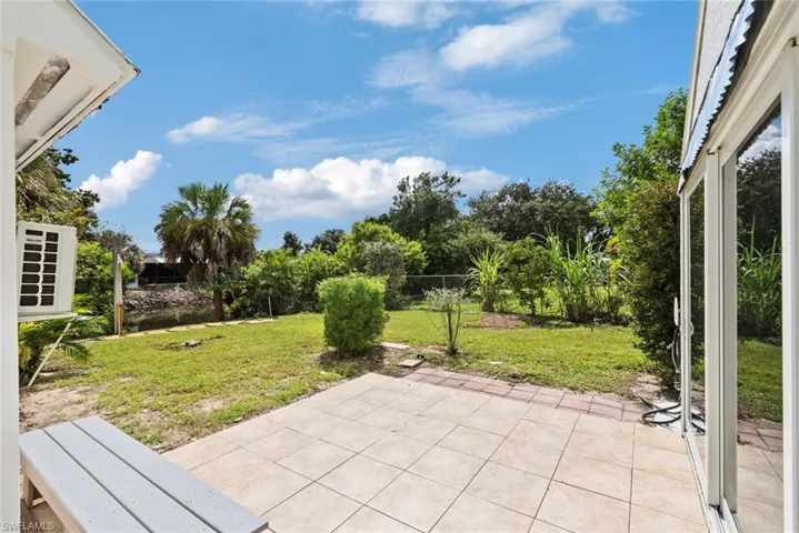 Tiled patio area with direct access to a grassy yard, mature trees and a canal view