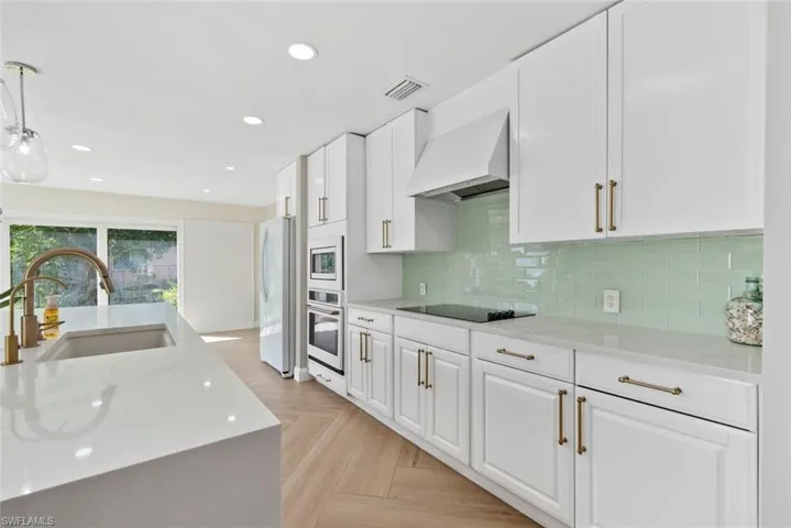 Kitchen featuring white cabinetry, light-toned countertops,  tile backsplash