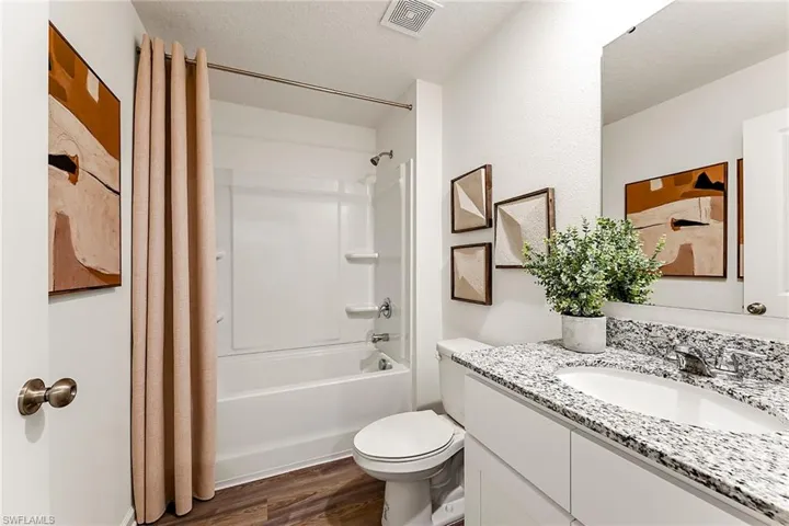 Photos are of a model home or artist rendering. Home may be virtually staged; Full bathroom with wood-type flooring, a textured ceiling, shower / tub combination, vanity, and toilet