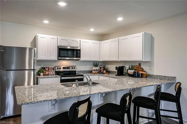 Photos are of a model home or artist rendering. Home may be virtually staged; Kitchen featuring stainless steel appliances, sink, kitchen peninsula, and white cabinetry