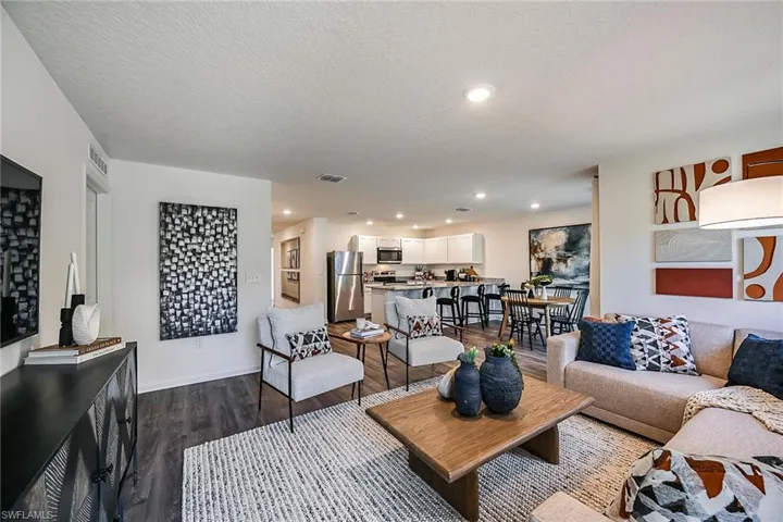 Photos are of a model home or artist rendering. Home may be virtually staged; Living room featuring a textured ceiling and dark hardwood / wood-style flooring