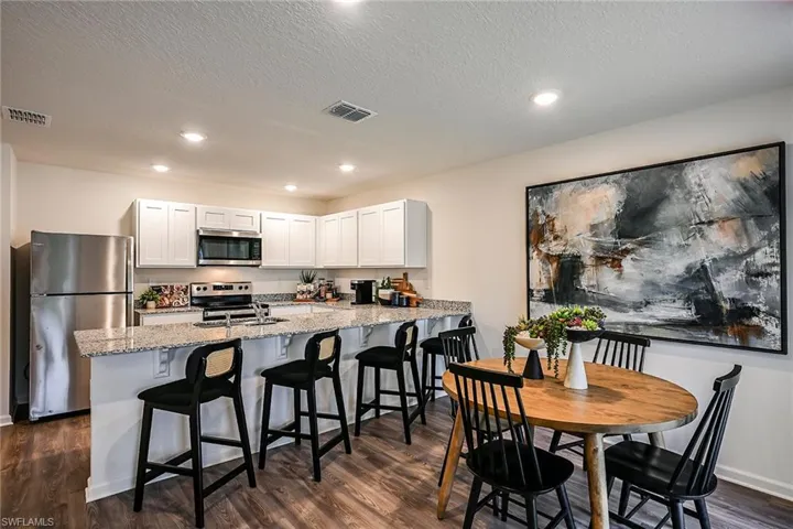 Photos are of a model home or artist rendering. Home may be virtually staged; Dining room with a textured ceiling, dark hardwood / wood-style flooring, and sink