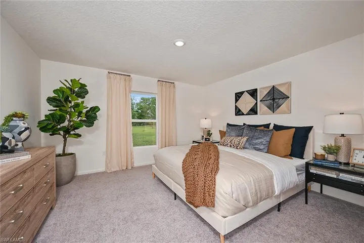 Photos are of a model home or artist rendering. Home may be virtually staged; Bedroom featuring a textured ceiling and light colored carpet