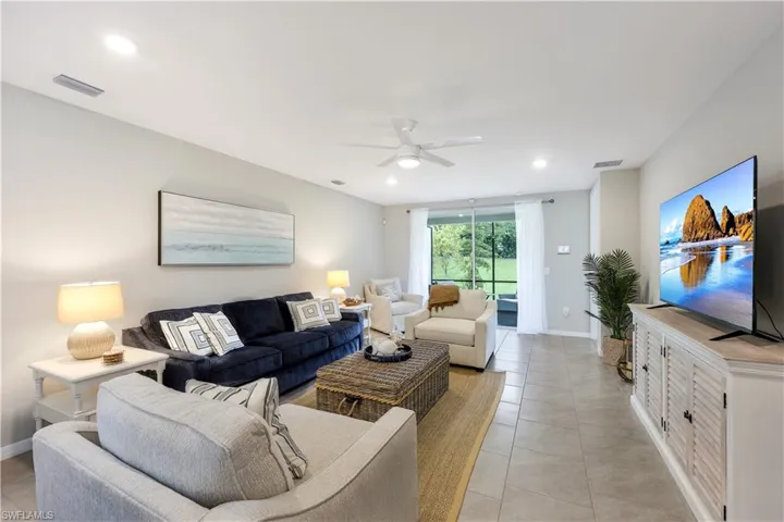 Living room with a ceiling fan, light tile patterned floors, and recessed lighting