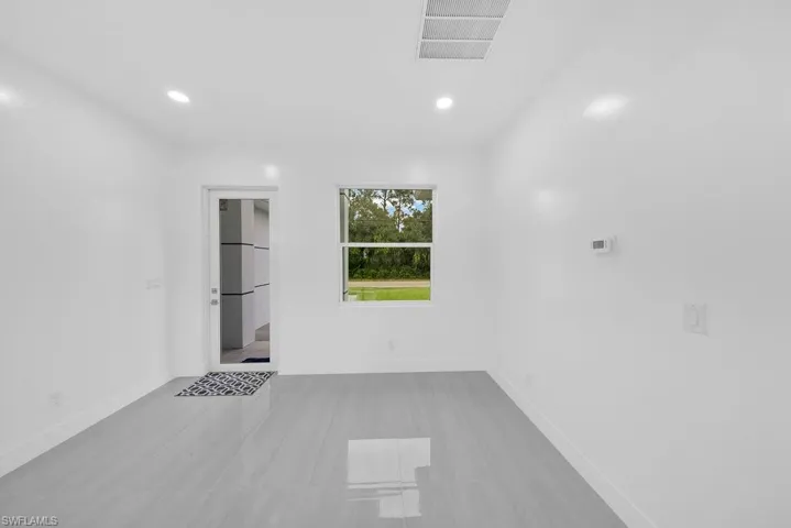 Interior space featuring light-toned tile flooring, recessed lighting, a glass-panel entry door, and a dual-pane window