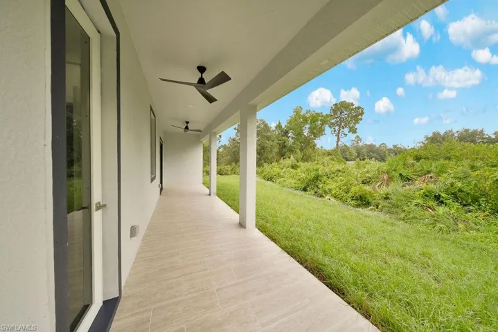 Covered outdoor patio featuring tile flooring, ceiling fans, and support columns