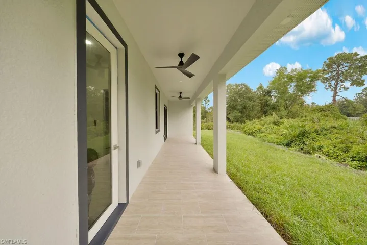 Covered porch featuring tile flooring, structural columns, ceiling-mounted fans, and access via glass-paneled exterior doors