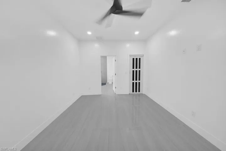 Neutral interior space featuring wood-finish flooring, recessed lighting, ceiling fan, and a multi-pane glass door