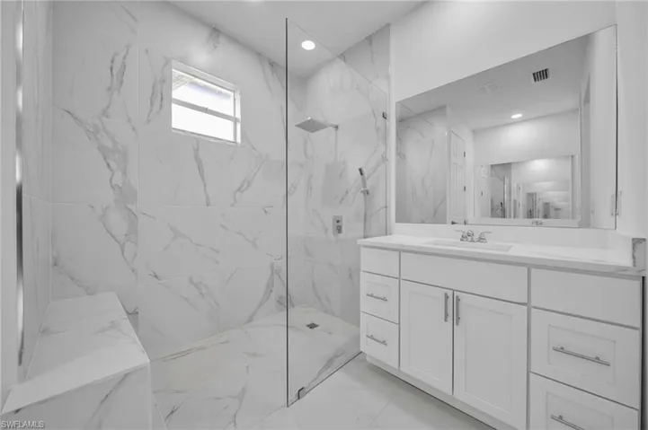 Bathroom with vanity, a marble finish shower, recessed lighting, and light marble finish floors